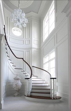 an elegant staircase with chandelier and white walls