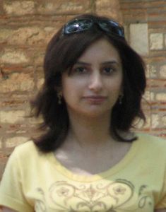 a woman with sunglasses on her head is standing in front of a brick wall and looking at the camera