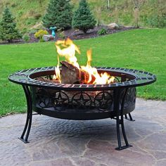 a fire pit sitting on top of a stone patio next to a lush green field