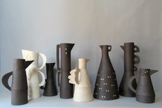 a group of vases sitting next to each other on a white counter top in front of a wall