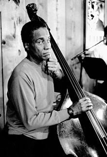 a black and white photo of a man holding a bass