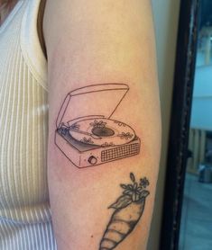 a woman's arm with a tattoo of a record player and a carrot