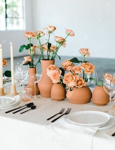 there are many vases with flowers in them sitting on the dining room table set for dinner