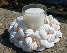 a candle and some seashells on a rock