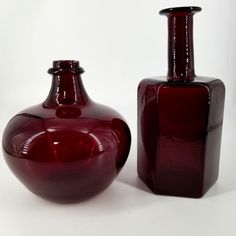 two red vases sitting next to each other on a white surface