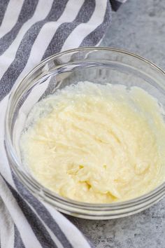 a glass bowl filled with batter sitting on top of a counter next to a towel