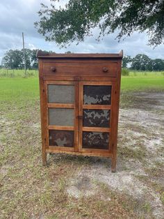 an old wooden cabinet sitting in the middle of a field