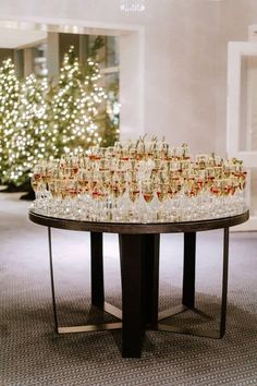 a table filled with champagne glasses on top of a carpeted floor next to a christmas tree