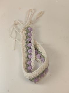 two crocheted bracelets are sitting on a white surface, one is purple and the other is green