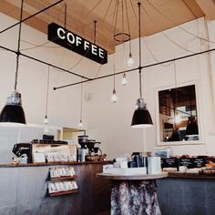 a coffee shop with lights hanging from the ceiling