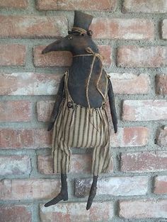 an old fashioned doll hanging on a brick wall with a top hat and striped pants