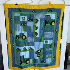 a blue and yellow quilt with tractors on it hanging from a hook in a closet