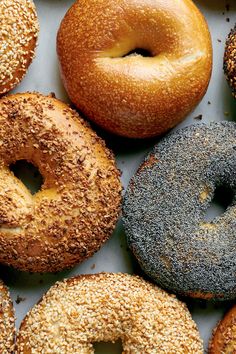 many different types of donuts on a white table top with sesame sprinkles