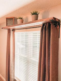 there is a window with some plants on top of it and the blinds are closed