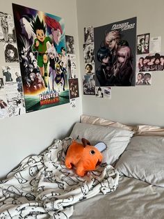 an unmade bed with posters on the wall and a stuffed animal laying on it