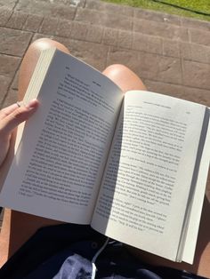 someone is reading a book while laying on the ground