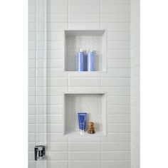 two blue cups sitting on top of a shelf in a white tiled shower stall next to a toilet