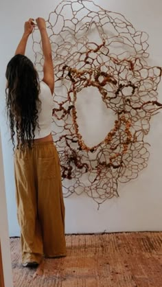 a woman standing in front of a wall sculpture