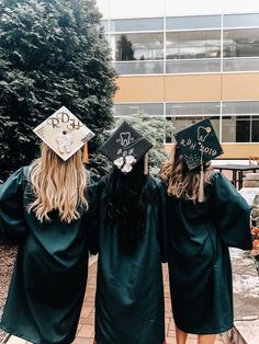 two girls wearing graduation caps and gowns are standing in front of a building with their arms around each other