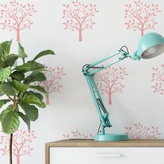 a desk lamp sitting on top of a wooden table next to a potted plant