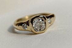 a yellow gold ring with three diamonds on it's sides, sitting on a white surface