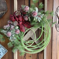 a christmas wreath is hanging on the side of a wooden door with rope and flowers