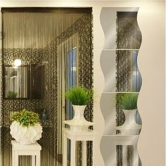 two white vases with plants in them sitting on a shelf next to a mirror