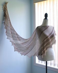 a knitted shawl on a mannequin next to a window