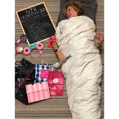 a woman laying in bed with shopping bags and a chalkboard on the wall behind her