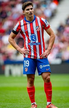 a man standing on top of a soccer field wearing a red and blue striped shirt