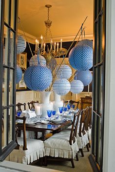 a dining room table with blue and white balls hanging from it's centerpiece