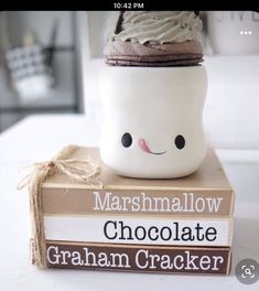 a stack of books sitting on top of a table next to a cup filled with whipped cream