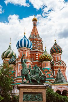 a statue in front of a building with domes on it's sides and a blue sky background