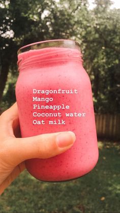 a hand holding a pink smoothie in a jar with the words dragon fruit mango pineapple coconut water oat milk