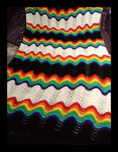 a multicolored crocheted blanket sitting on top of a bed