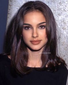 a close up of a person with long hair and brown eyeshadow wearing a black top