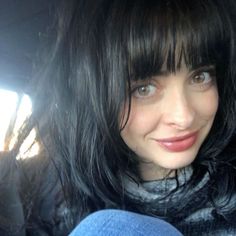 a close up of a person in a car with long black hair and wearing a scarf