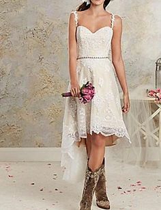 a woman in a short white dress and cowboy boots is posing for the camera with her bouquet