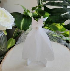 a white wedding dress on top of a piece of wood with flowers in the background