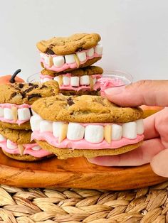 a person holding three cookies with marshmallows on them