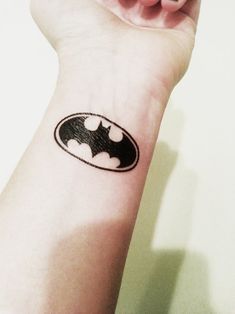 a small batman symbol tattoo on the wrist