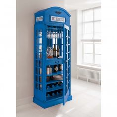 a blue phone booth with bottles and glasses on it's shelves in a white room