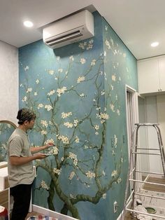 a man is painting a mural on the wall in his room with blue and white paint