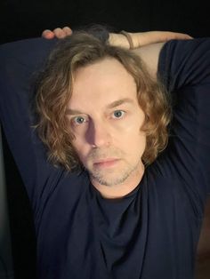 a man with long hair and blue eyes posing for the camera