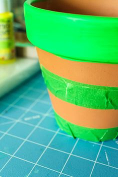 a green and orange planter sitting on top of a table next to a blue cutting board