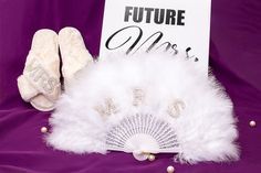 a fan and some white slippers on a purple cloth next to a sign that says future mrs