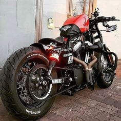 a red and black motorcycle parked in front of a building