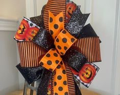 an orange and black halloween bow on top of a wooden table next to a chair