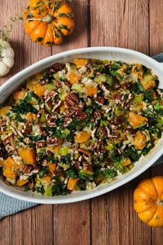 a casserole dish with pumpkins and pecans in the background on a wooden table