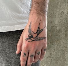 a man's hand with a bird tattoo on it